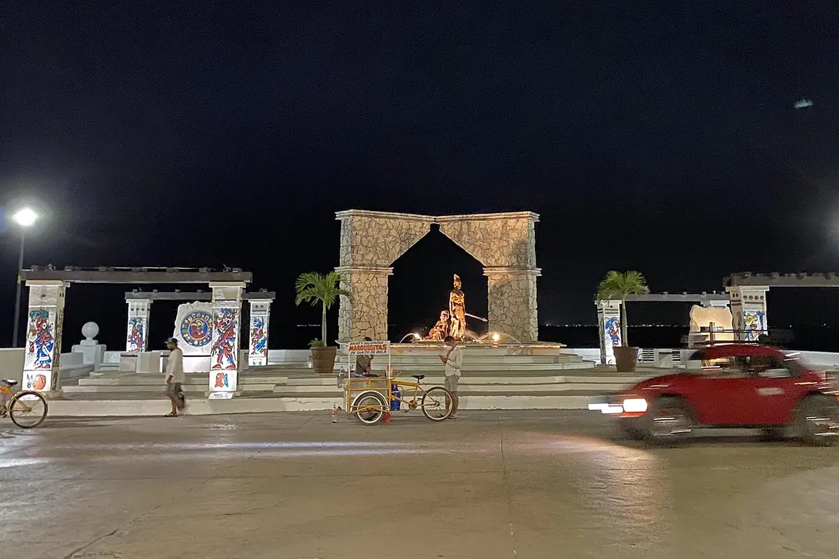 The San Miguel de Cozumel malecón at night, with a stone arch lit in the background