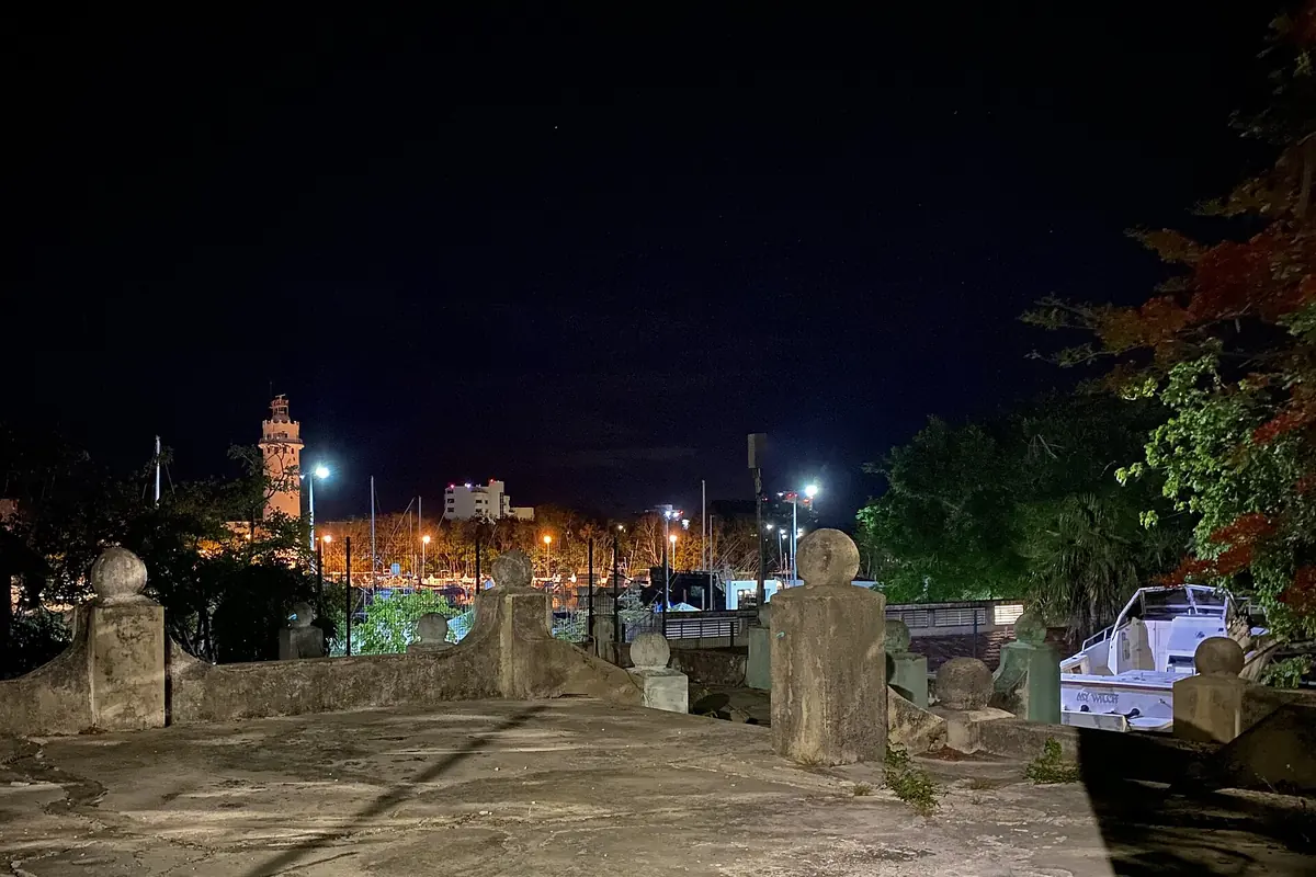 San Miguel de Cozumel at night, with the town's lights beyond a stone walkway